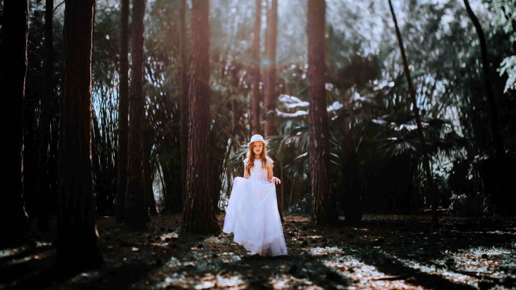 Natural Light Photography Tips: How to Work With the Light You Already Have 3 - Blue Bend Photography Girl in a white dress posing in a forest with natural backlight streaming through the trees