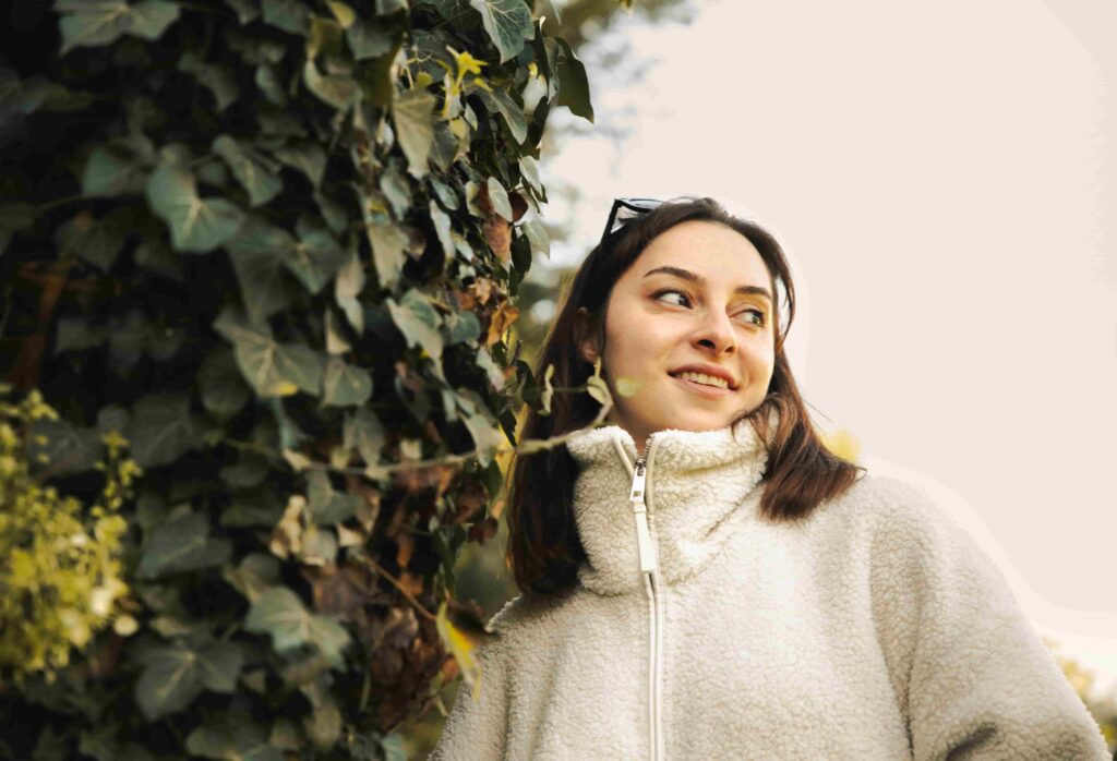 Portrait Photography Tips: Techniques, Settings & Lighting for Beginners 1 - Blue Bend Photography Young woman smiling outdoors beside ivy wall — natural light outdoor portrait photography
