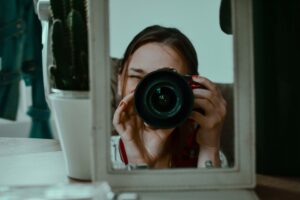 Photographer taking a mirror selfie with a DSLR camera — portrait photography tips